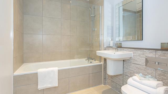 Modern bathroom with beige tiles and white ceramic goods.