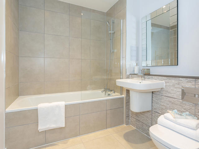 Modern bathroom with beige tiles and white ceramic goods.